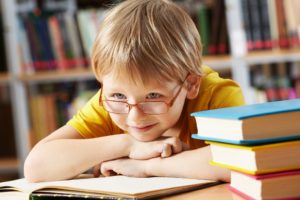 Boy leaning on books smiling