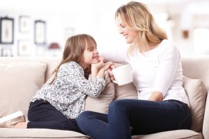 Image of a mother and daughter sitting together on couch and talking.
